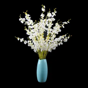 Artificial dancing orchid flower detail showing white silk blooms in a blue ceramic vase.