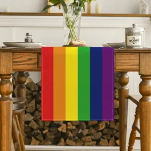 Rainbow linen table runner detail showing vibrant multi-color stripes on rustic wooden dining table.