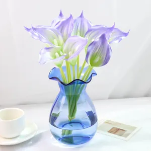 Vue détaillée de calla artificiel en PU, jolies fleurs de lys violettes dans un vase bleu.