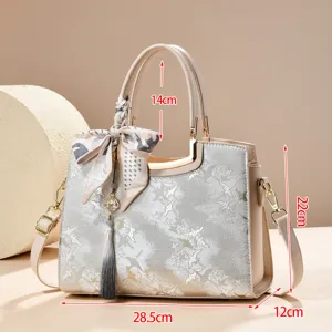 Detail view of the embroidered handbag showing dimensions, tassel charm and crane pattern.