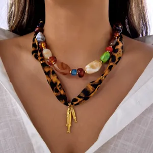 Primer plano de collar doble con cuentas multicolores y pañuelo de leopardo con peces.