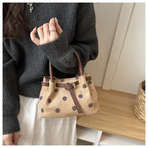 Borsa a mano in camoscio a pois retro, dettaglio manico marrone e fibbia, elegante accessorio.