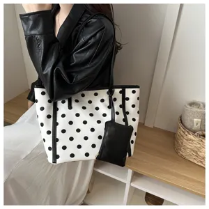 Dettaglio in primo piano della borsa tote in tela a pois bianchi e neri con pochette.
