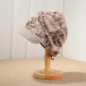 Nahaufnahme Detail der Damen Vintage Batik Slouchy Beanie Mütze mit Metallabzeichen kurzer Schirm.
