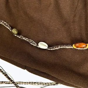 Nahaufnahme einer bohemian vintage Strickmütze mit geflochtener Kordel und Perlen.