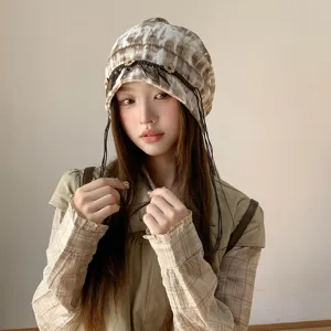 Detailansicht der ethnischen Batik-Slouchy-Mütze mit zarten Quasten und süßen Blumenanhängern.