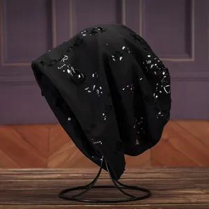 Nahaufnahme Detailansicht der schwarzen distressed Strickmütze mit silbernen Farbklecksen.