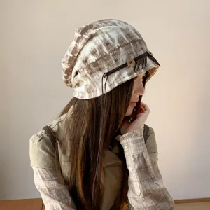 Nahaufnahme der ethnischen Batik Schlupfmütze mit geflochtenem Riemen und Holzblumenanhänger.
