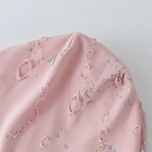 Nahaufnahme der rosa distressed Strickmütze mit metallic-silbernen Details für den Trend.