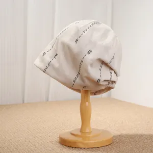 Nahaufnahme der beigen Beanie Mütze mit modischem Buchstaben und gestrichelten Linien.