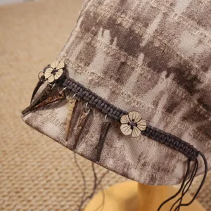 Nahaufnahme eines ethnischen Batik-Slouchy-Hutes mit Holzblumen-Anhängern und Flechtband.