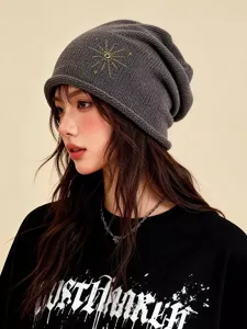 Vue détaillée d'un bonnet en tricot gris foncé avec une broderie dorée délicate.