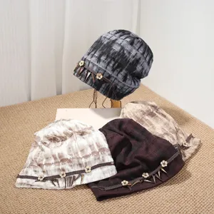 Nahaufnahmen von ethnischen Batik-Slouchy-Mützen mit Holzblumenknöpfen und Fransen.