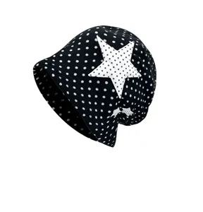 Detail view of black polka dot beanie hat with large star patch, trendy cute soft breathable fabric.