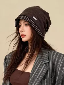 Detailaufnahme der gestreiften Oversize Beanie Mütze mit weicher Textur und Metall-Label.
