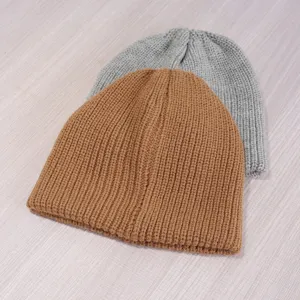 Close up detail of winter thick knitted beanie hats in camel and grey colors, warm and cozy.