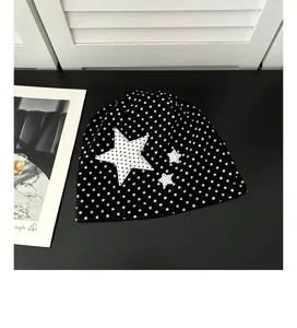 Detailed close-up view of the black and white polka dot beanie showcasing cute white star patches.