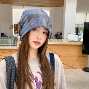 Detail view of the cozy blue tie-dye slouchy beanie worn by model in modern indoor setting.