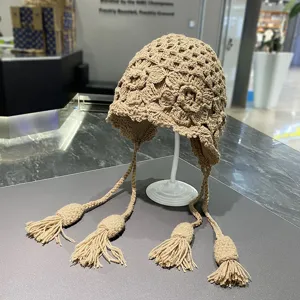 Handgefertigte beige Häkel Strickmütze mit Ohrenschützern und langen Quasten für Damen.