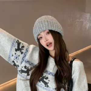 Detalle de un cómodo gorro de punto gris usado por la modelo en estilo de invierno.