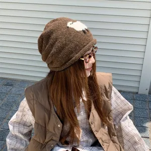 Nahaufnahme der braunen Strickmütze mit süßem weißem Schaf-Motiv, gemütlicher Herbststil.