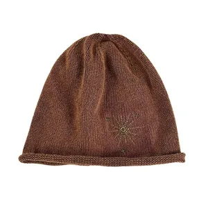 Gros plan detaille du bonnet en tricot marron avec decoration de rivets etoiles.