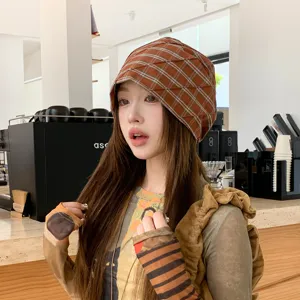 Vista detallada de un gorro plisado a cuadros marrones, con tela suave y textura elegante.