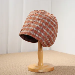 Vista detallada del gorro plisado a cuadros naranjas, mostrando la textura única del tejido.