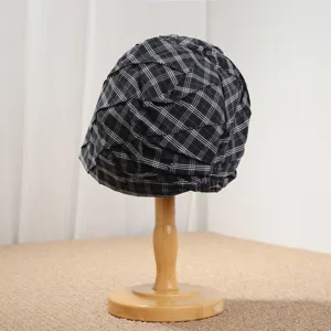 Vista detallada del gorro plisado a cuadros con textura única y diseño elegante en blanco y negro.