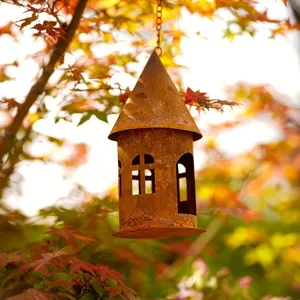 Rustic metal house candle holder lantern hanging outdoors, vintage garden decor detail.