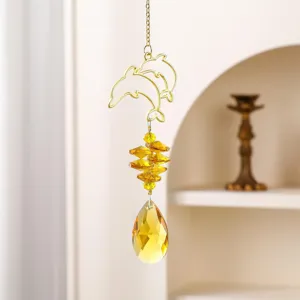 Dettaglio ravvicinato di un acchiappasole in cristallo con delfino dorato e luminose perle.