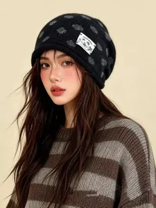 Detailansicht einer stylischen schwarzen Strickmütze mit grauen Punkten und weißem Stoffetikett.