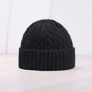 Vista detallada de un gorro negro de punto de trenzas, sombrero de invierno clásico.