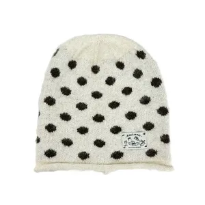 Nahaufnahme Detail der kuscheligen Strickmütze mit Punkten und dem Markenstoffetikett.