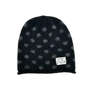 Nahaufnahme der schwarzen Strickmütze mit grauen Punkten und individuellem Stoffetikett.