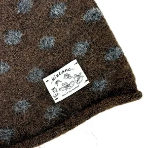 Nahaufnahme der braunen Strickmütze mit grauen Punkten und gewebtem Etikett.