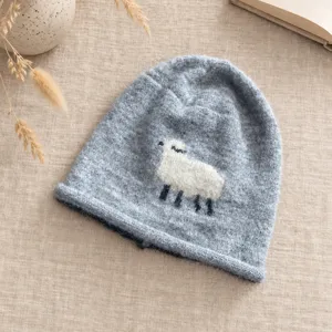 Detailaufnahme einer süßen hellblauen Strickmütze mit niedlichem weißen Schafmotiv, gemütlich.
