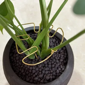 Gold metal monstera leaf plant support detail, showcasing decorative design inside flowerpot.