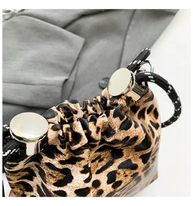 Close-up detail of leopard print women pouch bag with metal hardware and black drawstring.