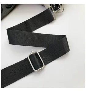 Detailed shot of black woven shoulder bag strap with silver metal adjustable hardware.