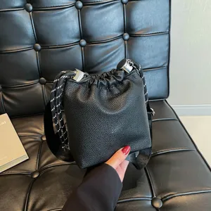 Detailed view of the trendy black leather bucket shoulder bag with drawstring closure.