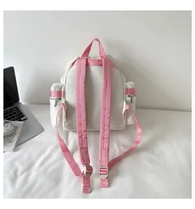 Élégant sac à dos blanc avec bretelles roses et poches latérales pour voyage et école.