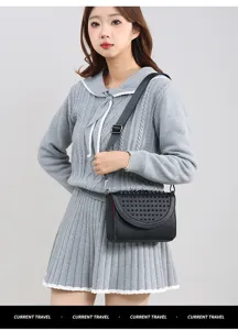 Detailed shot of the stylish black studded crossbody bag worn with a chic grey knit outfit.