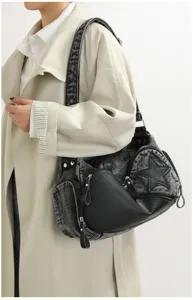 Stylish dark gray denim shoulder bag detail featuring star and leather patchwork with rivets.