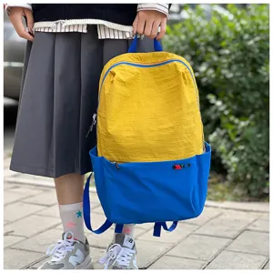 Detail shot of colorblock travel backpack, vibrant yellow and blue casual daypack with pocket.