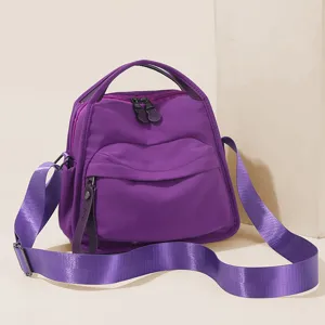 Purple nylon crossbody bag detail, featuring durable zippers, wide strap, and top handle.