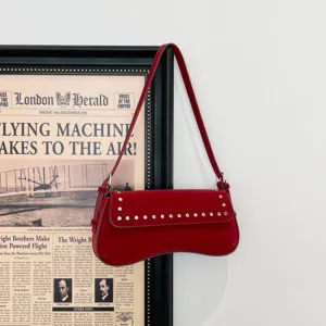 Chic red shoulder bag with metal rivets and unique curved design, stylish underarm bag.