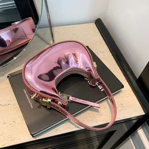Primo piano della borsa a mano rosa metallizzata lucida con manico curvo e finitura riflettente liscia.