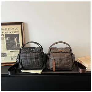 Detailed shot of casual plaid oxford shoulder bags in black and brown, showing zipper and pockets.