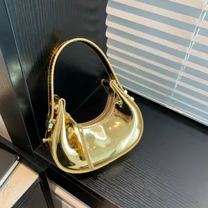 Vista dettagliata borsa mini dorata lucida, finitura specchiata, accessorio alla moda.